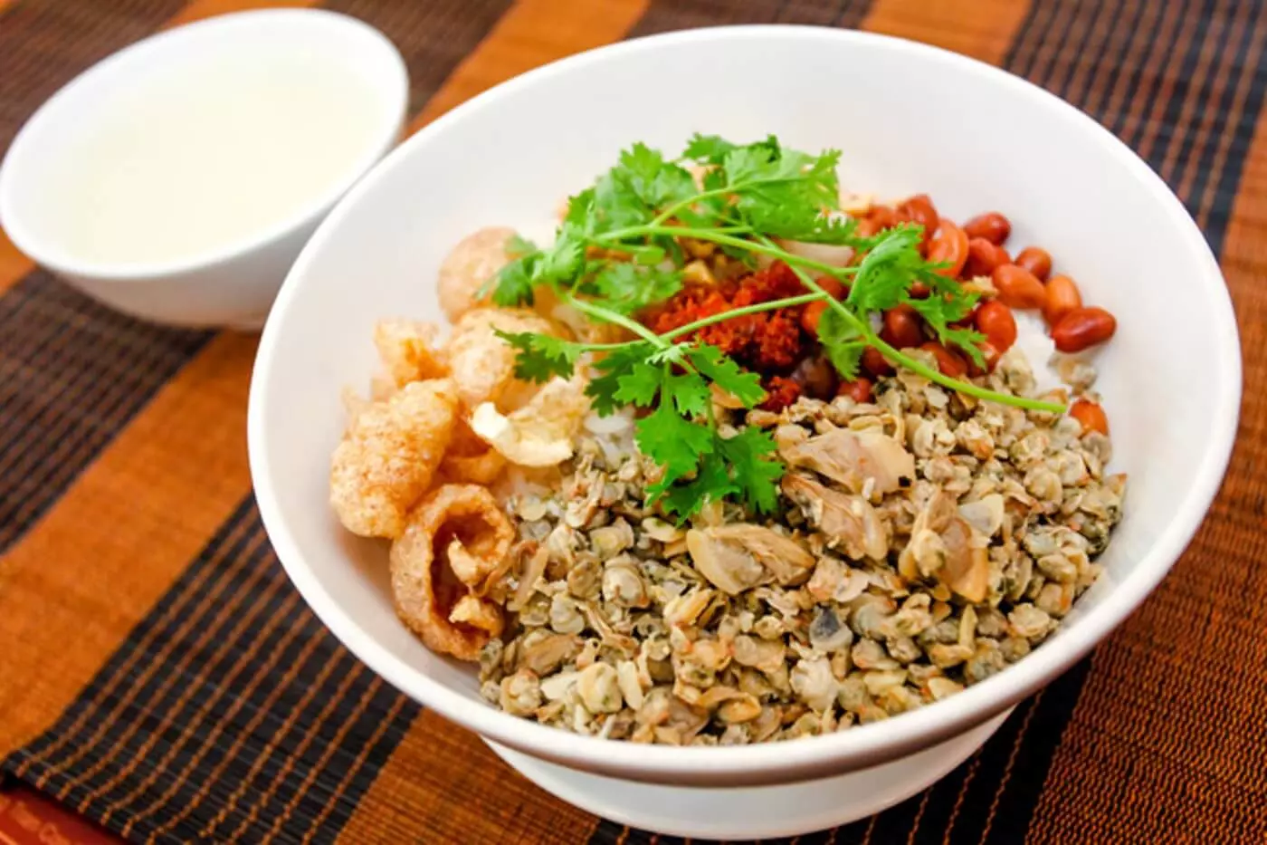 A plate of Clam Rice served with fresh herbs and dipping sauces.