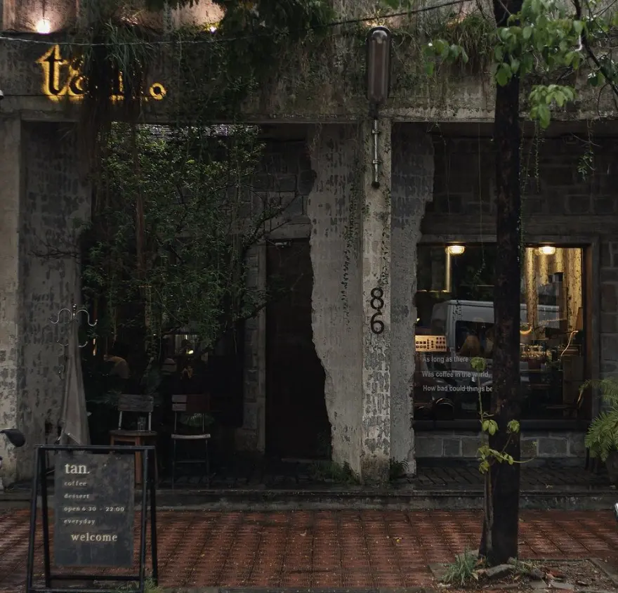 A cozy café in Hue with a view of raindrops falling outside the window, featuring a cup of salt coffee on the table.