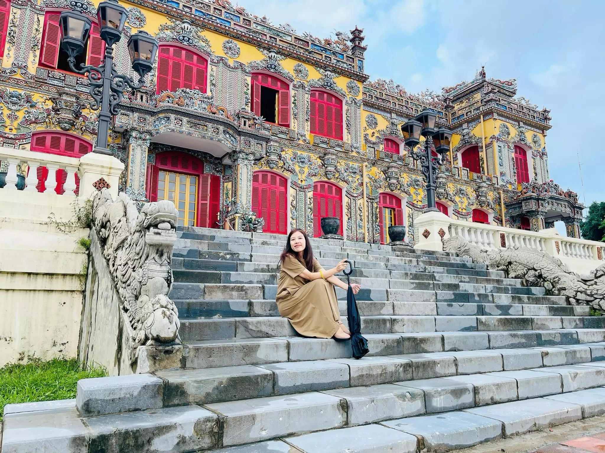 Garden of Kien Trung Palace with neatly pruned trees and a view of the dragon-adorned staircases at the front façade.