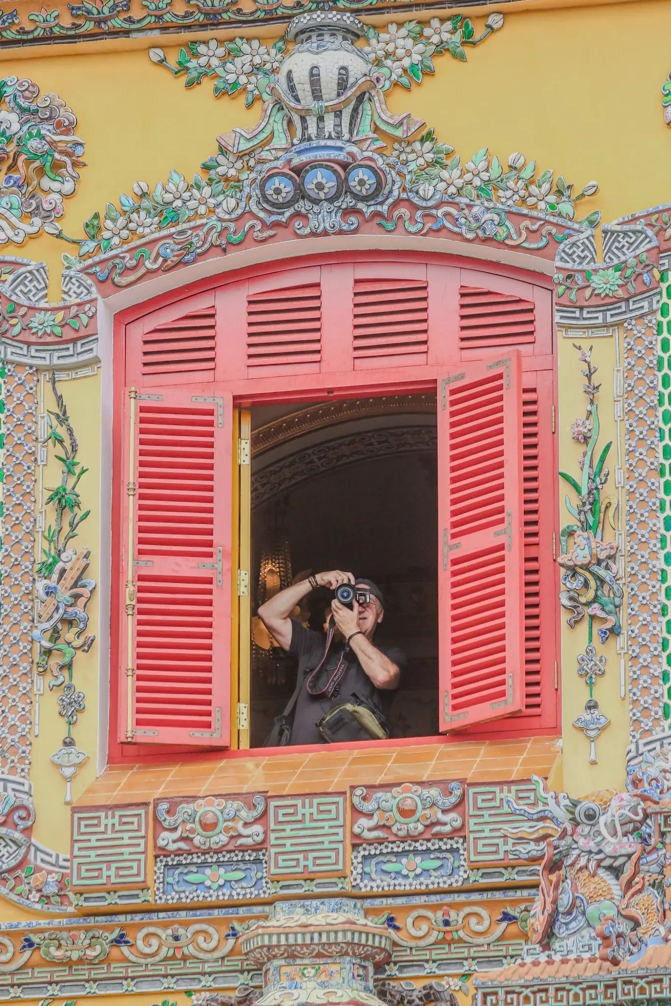 Close-up of the vibrant windows and golden glazed roof of Kien Trung Palace, showcasing intricate dragon mosaics and decorative patterns.