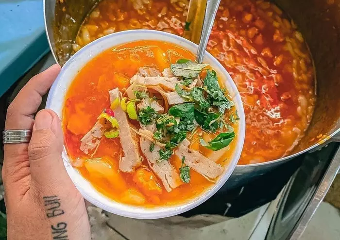 A bowl of Nam Pho Noodle Soup with shrimp and herbs.