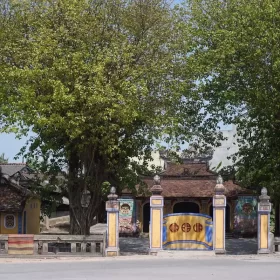 Bao Vinh Village Communal House in Hue, featuring moss-covered walls, a stone screen, and traditional architecture.