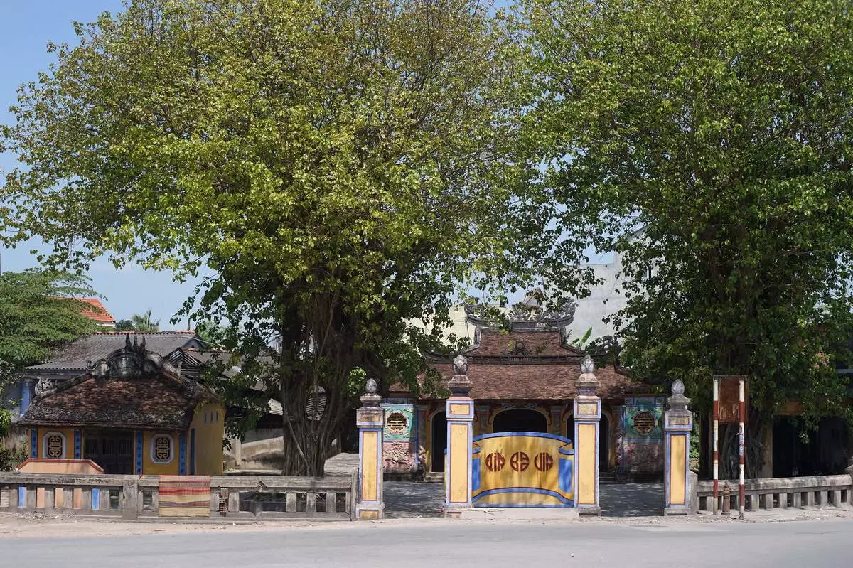 Bao Vinh Village Communal House in Hue, featuring moss-covered walls, a stone screen, and traditional architecture.