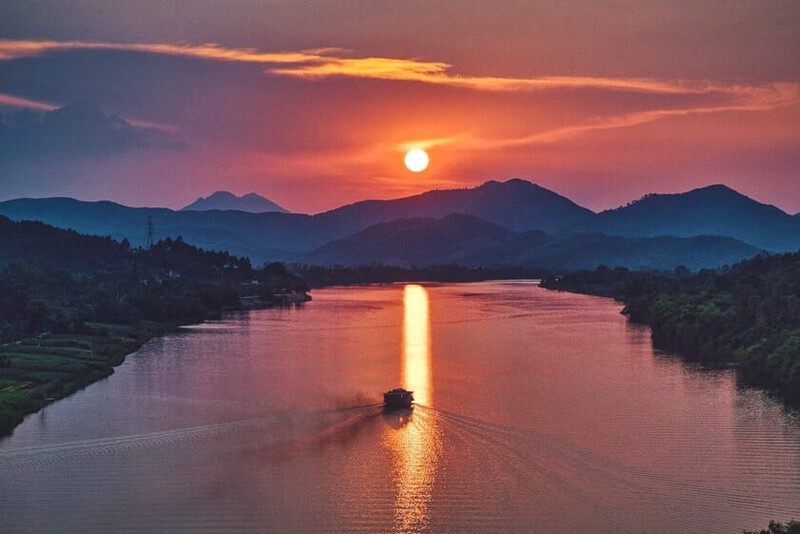 Sunset view of the Huong River in Hue with golden reflections on the water.